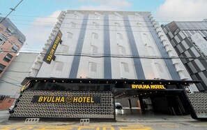 A hotel entrance with a modern facade, a prominent sign, and a covered driveway.