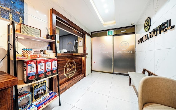 Un comptoir d’accueil au design en bois, un espace détente avec un fauteuil et une enseigne indiquant l’hôtel Byulha.