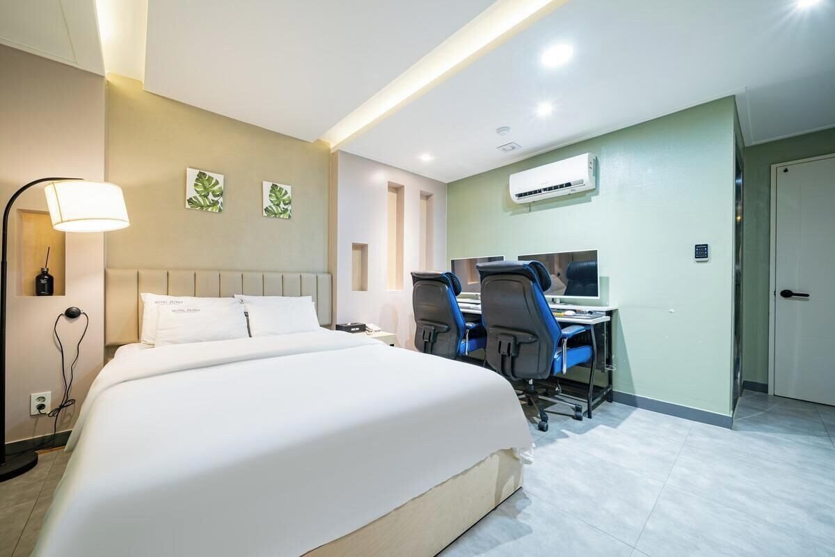 Ein Hotelzimmer mit Bett, Schreibtisch, Stühlen und einer Klimaanlage.