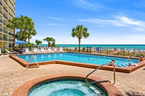 A swimming pool with lounge chairs and palm trees, overlooking a beach. - Renovated Beachfront Studio | Private Balcony, Pool & Direct Beach Access | $300 Free Fun Included (Panama City Beach)