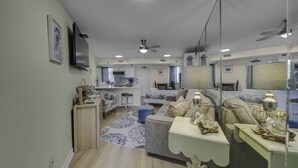 A modern living room with a sofa, coffee table, and a dining area with a table and chairs. - Renovated Beachfront Studio | Private Balcony, Pool & Direct Beach Access | $300 Free Fun Included (Panama City Beach)