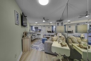 A modern living room with a sofa, coffee table, and a dining area with a table and chairs. - Renovated Beachfront Studio | Private Balcony, Pool & Direct Beach Access | $300 Free Fun Included (Panama City Beach)