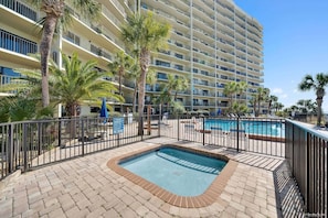 A hotel with a swimming pool, palm trees, and a multi-story building. - Renovated Beachfront Studio | Private Balcony, Pool & Direct Beach Access | $300 Free Fun Included (Panama City Beach)