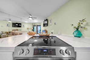 Une cuisine moderne dotée d’une plaque de cuisson à induction, d’une horloge numérique et d’un coin repas avec un îlot en marbre.