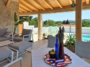 A covered outdoor seating area with stone walls, a pool, and a view of the mountains. - Villa MM Stankovci by Interhome (Pirovac)