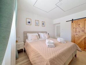 Ein Schlafzimmer mit einem Bett, einem Nachttisch, einem Holzschrank und drei gerahmten Bildern an der Wand.