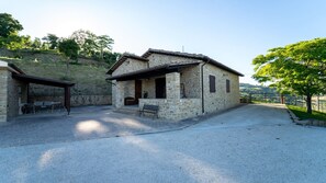 A stone building with a covered patio, a bench, and a table.