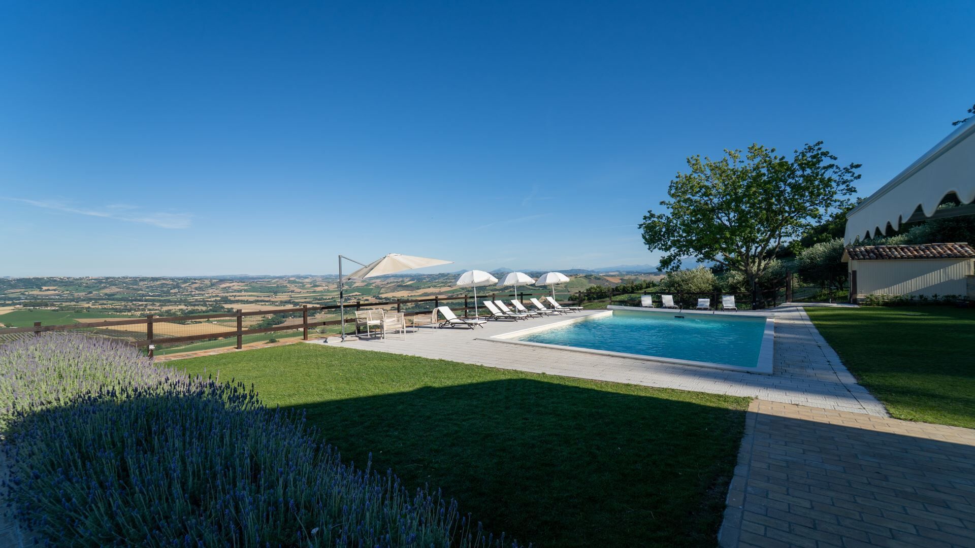 Une piscine avec des chaises longues, une vue dégagée sur le paysage et un espace clôturé.