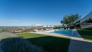 Une piscine avec des chaises longues, une vue dégagée sur le paysage et un espace clôturé.