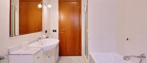 A bathroom with two sinks, a mirror, a bathtub, and wooden doors.