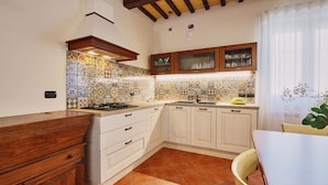 Una cocina con salpicadero de azulejos, armarios de madera, una estufa y una ventana con cortinas.