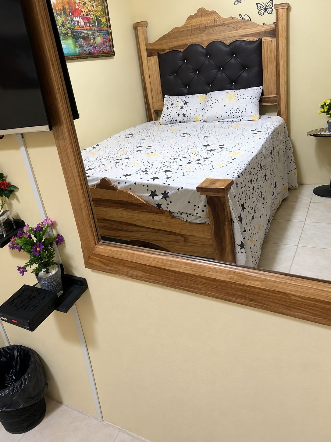 Un lit avec une tête de lit en bois et un couvre-lit blanc orné de motifs en forme d’étoiles.