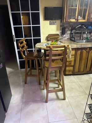 Une cuisine avec des chaises en bois, une table, un téléviseur et un meuble.