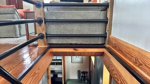 Una escalera de madera con vista a una habitación abajo.