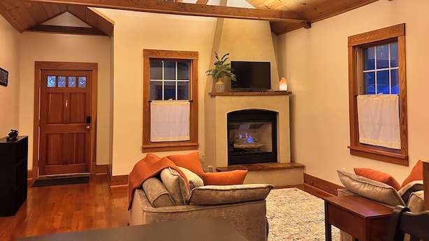 Una sala de estar acogedora con chimenea, vigas de madera y un televisor sobre la repisa.
