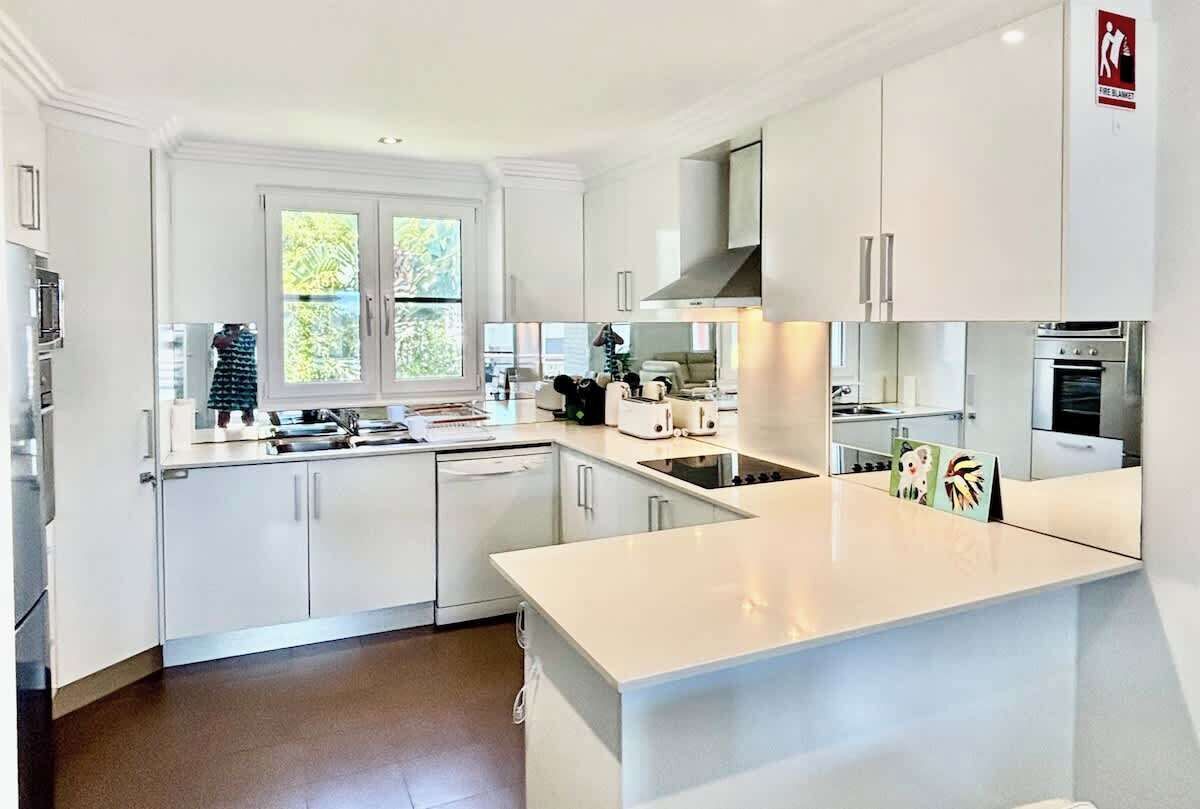 A modern kitchen with white cabinetry, a central island, and a window with a view.