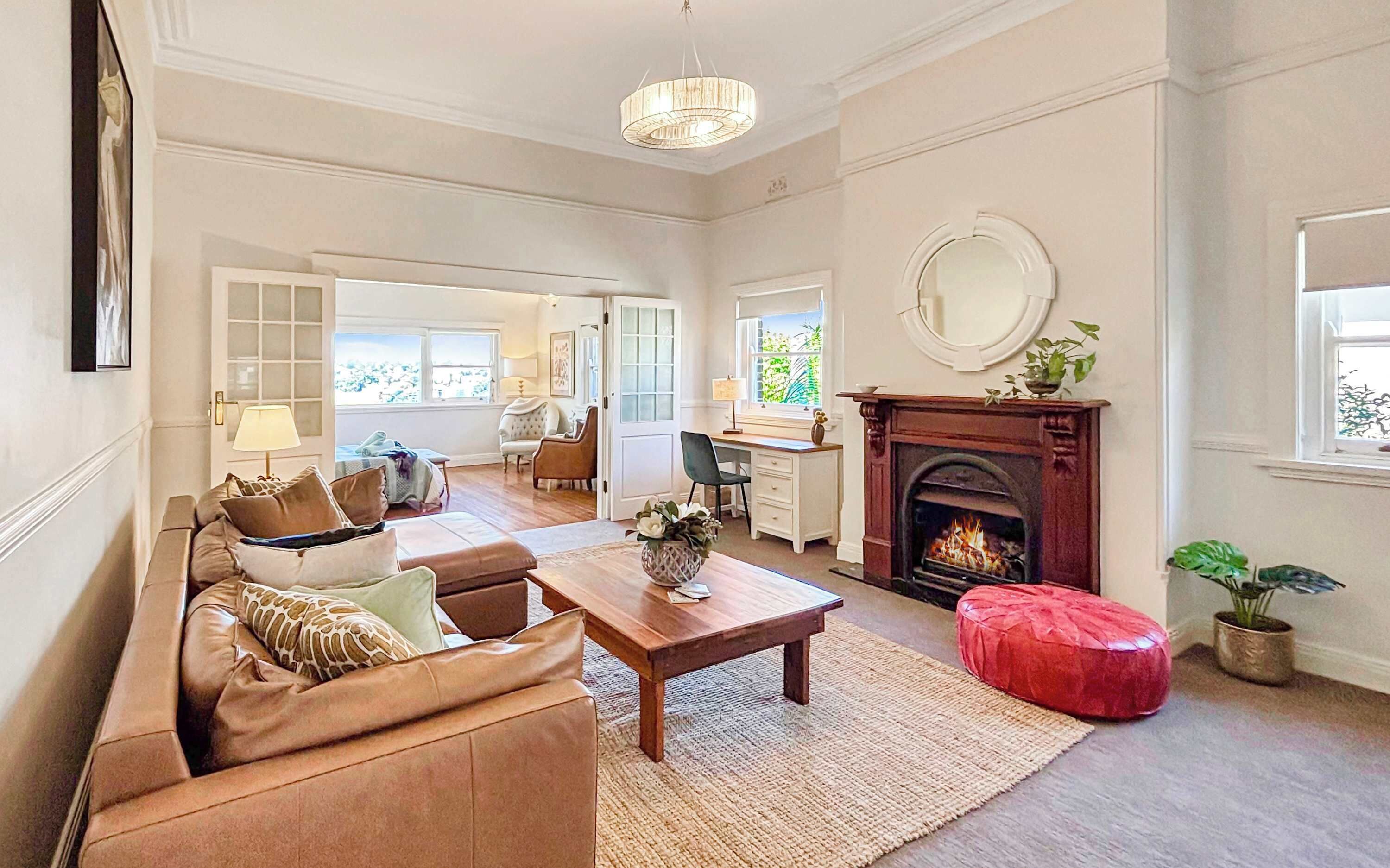 A spacious living room with a fireplace, a sofa set, a dining area, and a view of the outdoors.