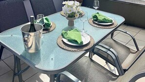 Ein Balkon mit Tisch für Zwei, einer Topfpflanze und einer Zierwand.
