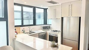 Eine moderne Küche mit Kochinsel, Edelstahlgeräten und Blick durch große Fenster.