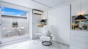 A modern interior with a white chair, a small table, and a lamp. - Upscale Studio in Kirribilli with private Terrace (Kirribilli)