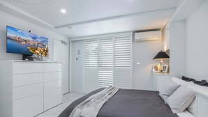 A bedroom with a bed, a TV on the wall, a wardrobe, and a window with blinds. - Upscale Studio in Kirribilli with private Terrace (Kirribilli)