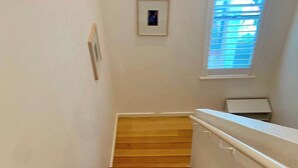 Eine Holztreppe mit Handlauf, weißen Wänden und einem kleinen gerahmten Bild an der Wand.