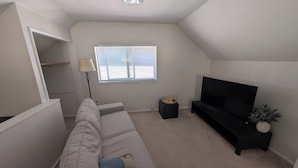 A living room with a sofa, a TV, a lamp, a window, and a ceiling fan. - Ballard Loft walking distance to everything (Seattle)