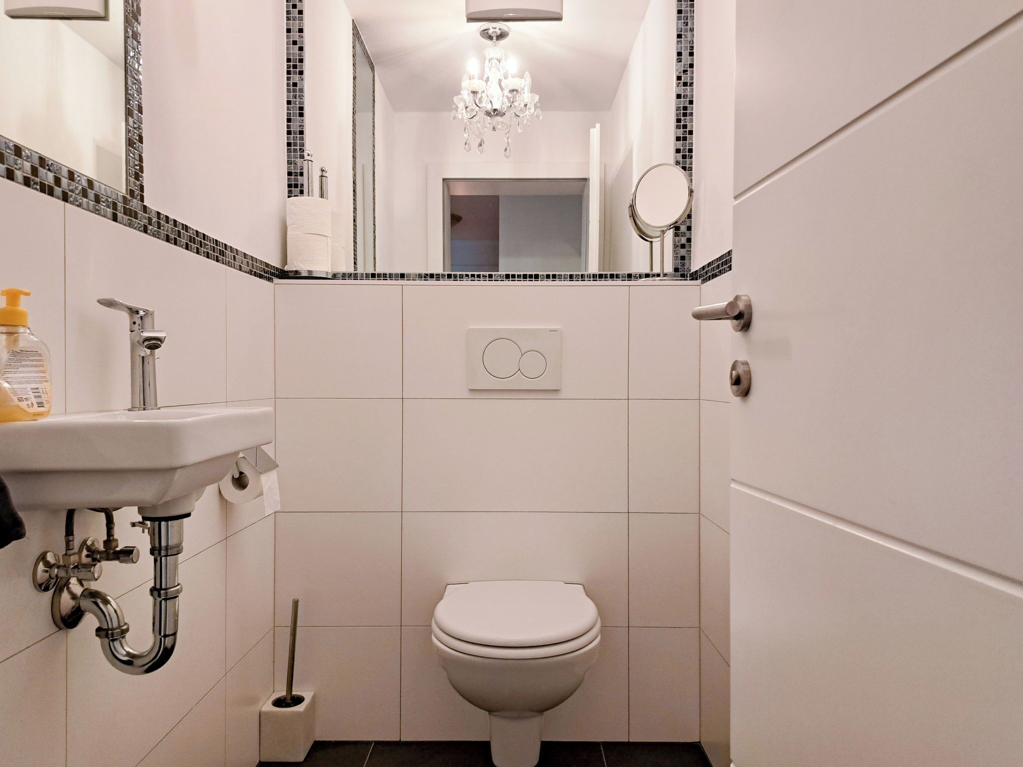 Ein Badezimmer mit Toilette, Waschbecken, Spiegel und einer Kandelaber.