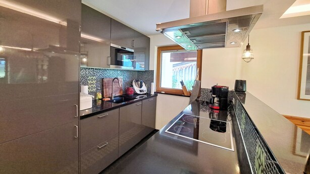Una cocina moderna con electrodomésticos de acero inoxidable, encimera negra y ventana con vistas.