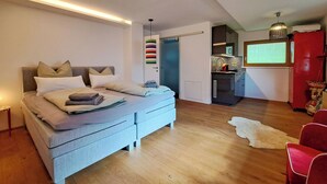 A modern bedroom with a bed, bedside tables, and a red chair. - Panorama by Interhome (Achenkirch)