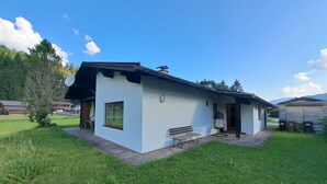 A small white building with a sloped roof, a bench, and a small table in front. - Panorama by Interhome (Achenkirch)