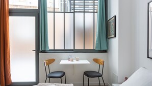 Ein Hotelzimmer mit einem Bett, einem kleinen Tisch mit Stühlen, einem Fenster mit Vorhängen und einer gerahmten Karte an der Wand.