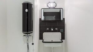 Ein Badezimmer mit einem schwarzen Warmwasserbereiter, einem weißen Waschbecken und einem Spiegel darüber.