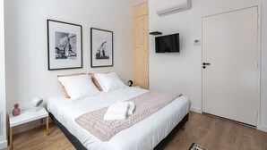 Ein Schlafzimmer mit einem Bett, zwei gerahmten Bildern, einem Fernseher und einer Klimaanlage.