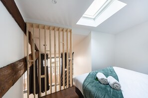 A bedroom with a skylight, a bed with a teal blanket, and a wooden staircase. - Modern AC duplex in the heart of Bordeaux (Bordeaux)