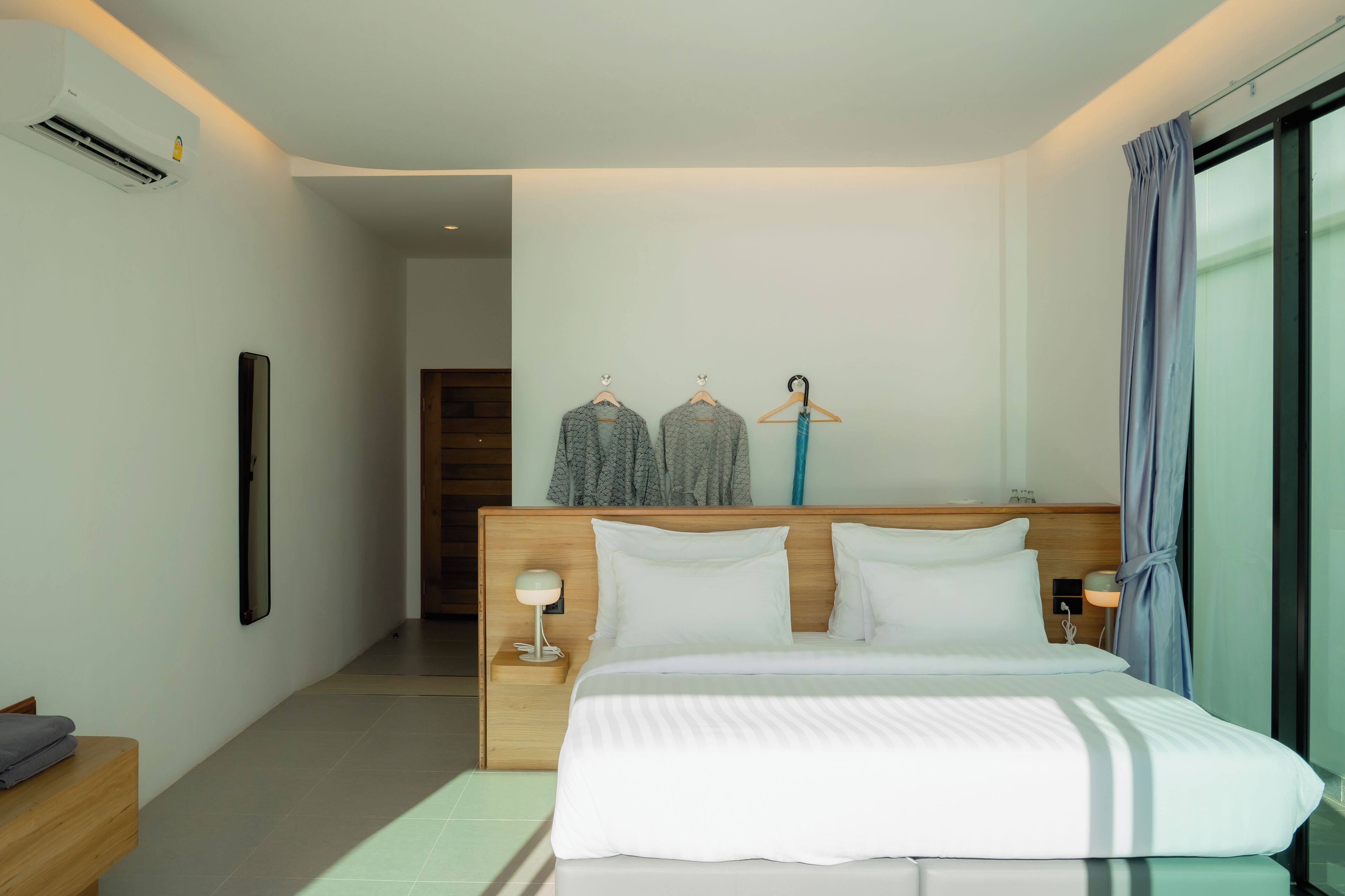 A modern hotel room with a large bed, bedside tables, a wardrobe, and a view of the outside.