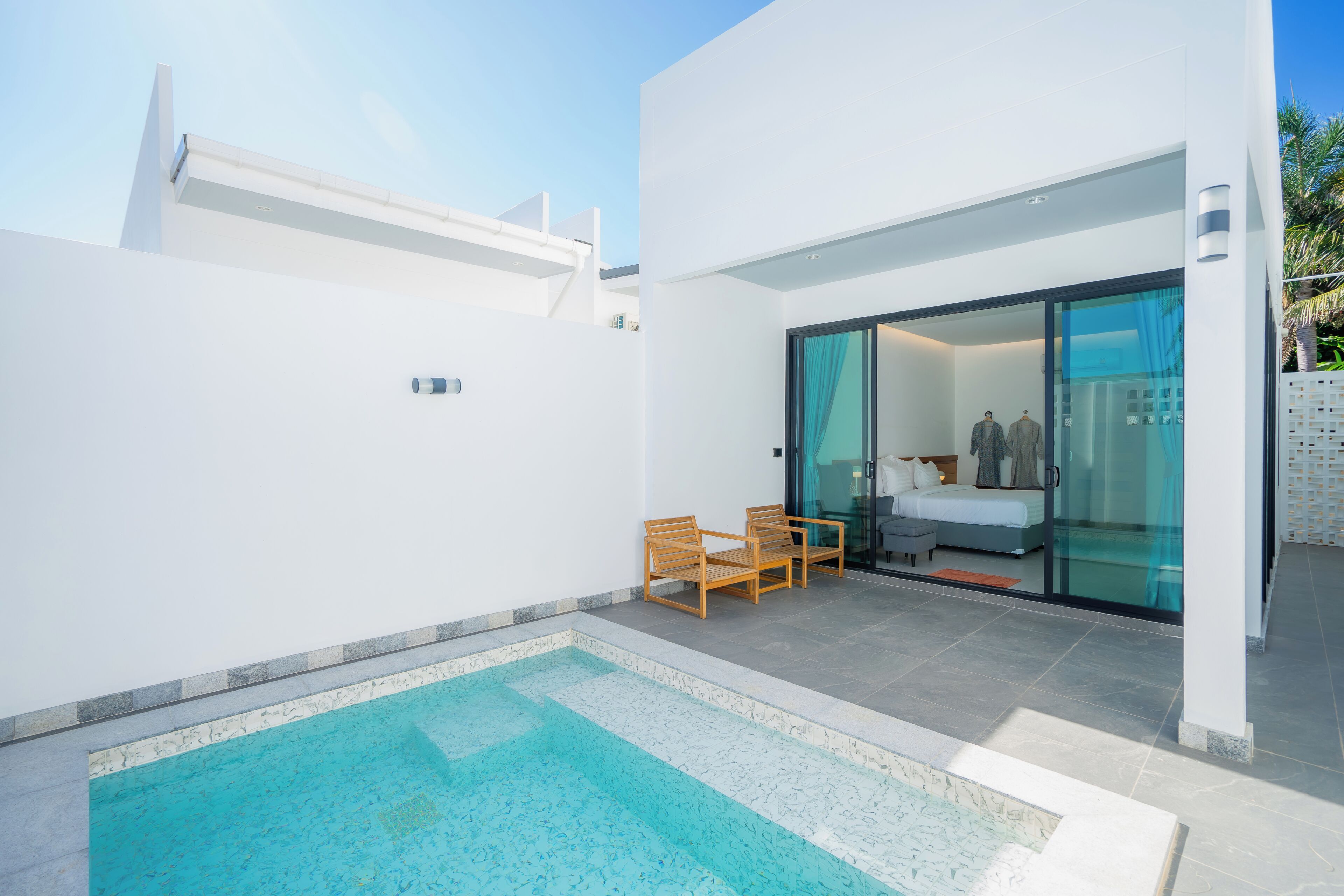 A modern outdoor pool area with a glass door leading to a bedroom.