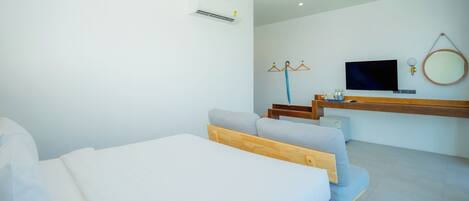 A modern hotel room with a bed, a TV, a mirror, and a wooden desk.