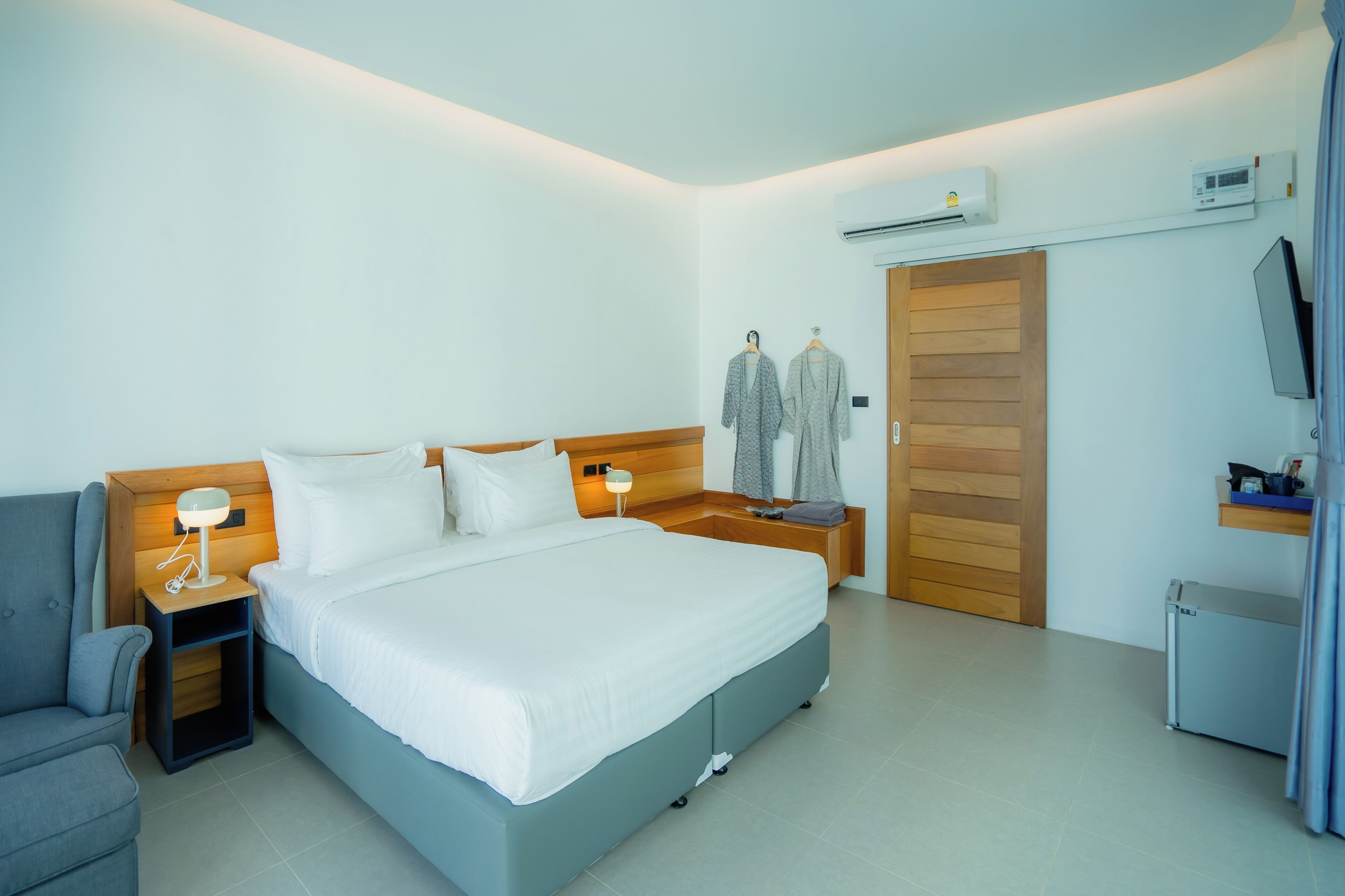 Een moderne hotelkamer met een bed, nachtkastjes, een stoel, een kledingkast en een airconditioner.