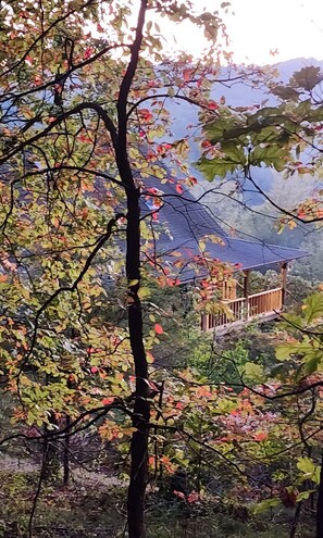 A mountainous landscape with a wooden structure, possibly a cabin or lookout, surrounded by trees with autumn foliage. - Entire 70 acre private Ozark Mountain Retreat. Sleeping room for TEN guests! (Pelsor)