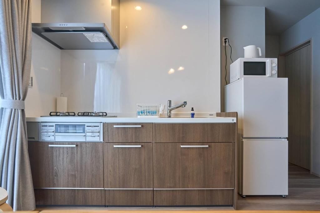 A modern kitchen with wooden cabinets, a built-in dishwasher, a microwave, and a refrigerator.