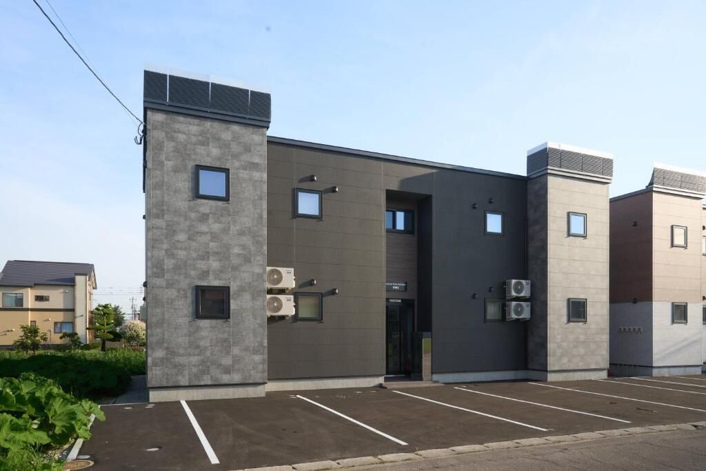 A modern building with a parking lot, air conditioning units, and a clear sky.