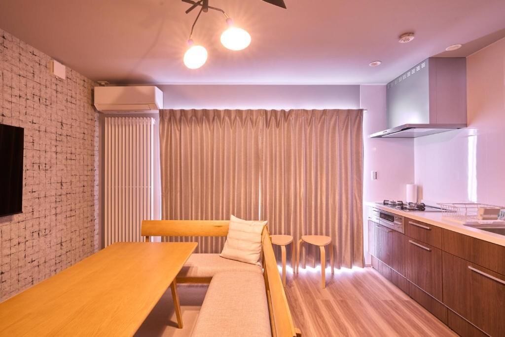 A modern kitchen with a wooden dining table, a bench, and a built-in oven.