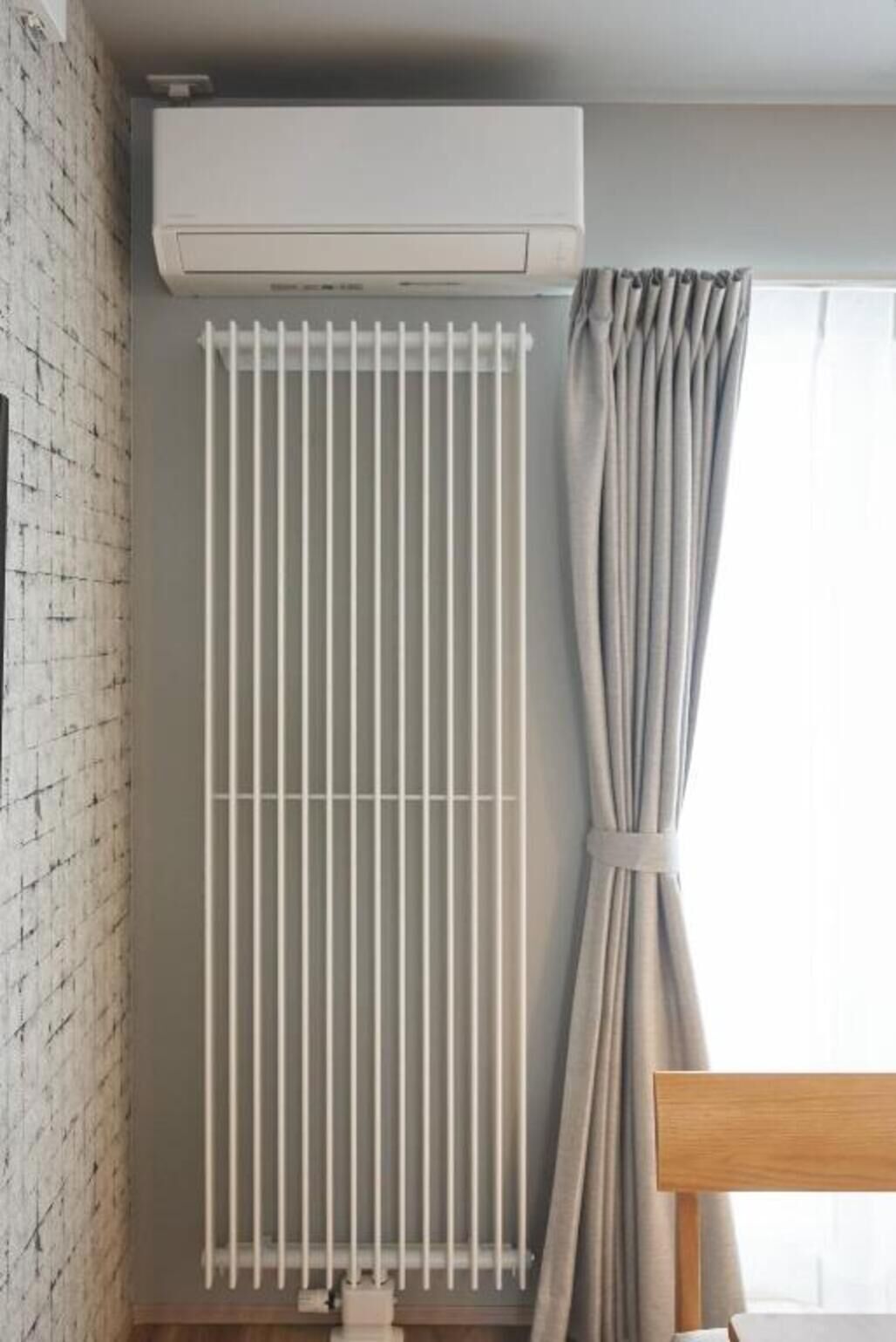 A room with a radiator, a curtain, and a brick wall.