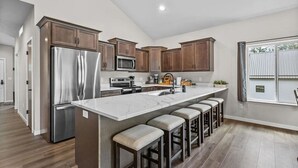 A modern kitchen with a large island, stainless steel appliances, and wooden cabinets.