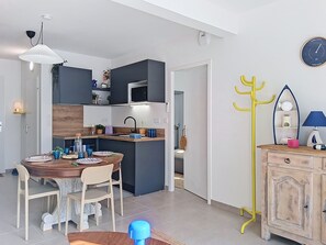 Eine moderne Küche mit dunklen Schränken, einer zentralen Kochinsel und einem Essbereich mit Holztisch und Stühlen.