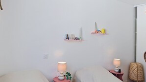 Makuuhuoneessa on kaksi sänkyä, yöpöydät lampuilla sekä seinälle kiinnitetyt hyllyt, joilla on koriste-esineitä.