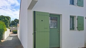 En vit byggnad med en grön dörr, nummer 26, och ett litet fönster med en gardin.