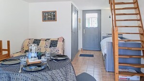 Ett möblerat rum med en soffa, ett matbord med stolar, en trappa och en dörr som leder till ett annat rum.