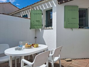 A white table with chairs and a window with green shutters. - Les Dunes by Interhome (Ile d'Oléron)